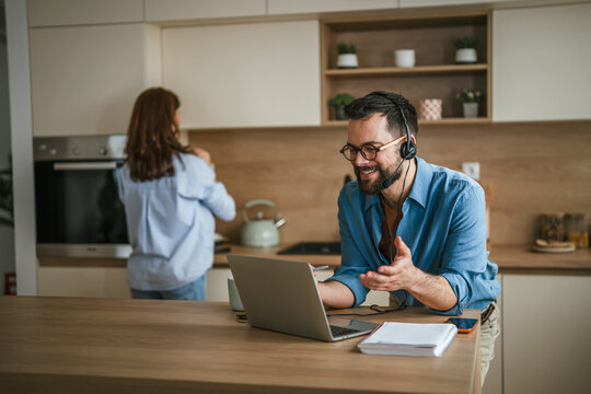 Man on video call working remotely at home kitchen