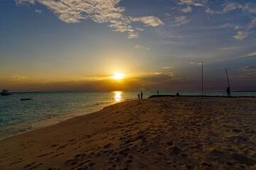 Obraz premium Golden sun dips low over calm turquoise sea