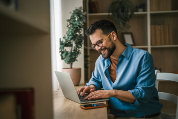 Man working on laptop from home office smiling