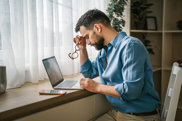 Man suffering from headache and stress working remotely