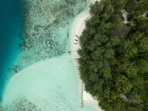 Aerial view of the serene Menjangan Kecil Island reveals a vibrant contrast between the deep blue sea and the light turquoise shallows, Karimunjawa, Central Java, Indonesia.