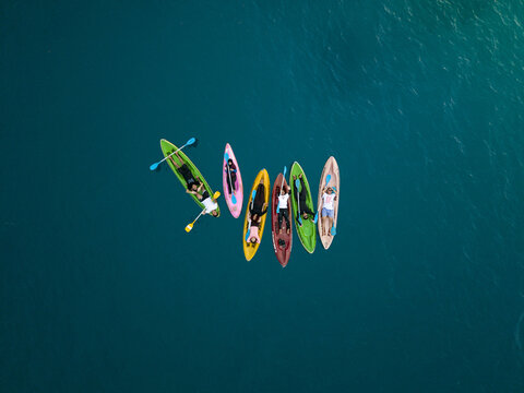 Aerial view of vibrant paddleboards cutting through the turquoise waters surrounding Menjangan Kecil Island, creating a striking contrast of colors, Karimunjawa, Central Java, Indonesia.