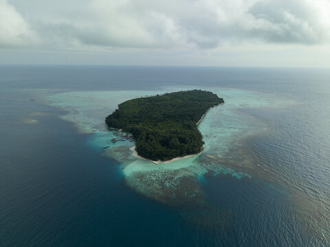 Aerial view of the lush green island surrounded by the turquoise and deep blue ocean waters, Menjangan Kecil Island, Karimunjawa, Central Java, Indonesia.