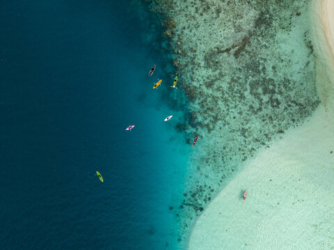 Aerial view of kayaks floating on the turquoise waters near Menjangan Kecil Island, where the ocean's depths meet the coral reefs, Karimunjawa, Central Java, Indonesia.