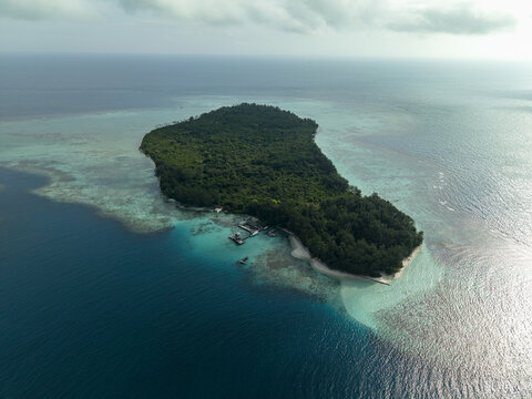 Aerial view of a lush, green island surrounded by turquoise and deep blue waters, Menjangan Kecil Island, Karimunjawa, Central Java, Indonesia.