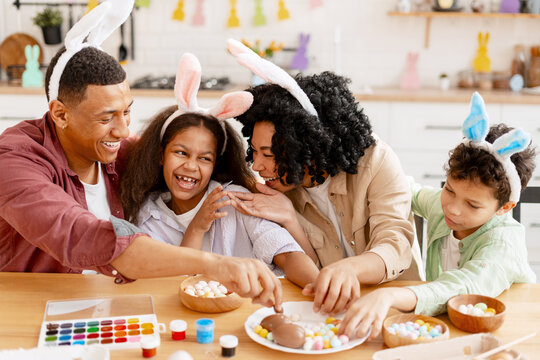Family wearing bunny ears enjoying Easter celebration, decorating eggs and having fun