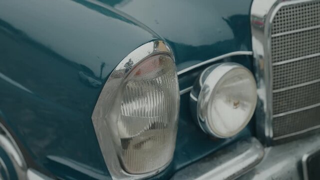 Close up of classic blue vintage car front with chrome grille and round headlight detail