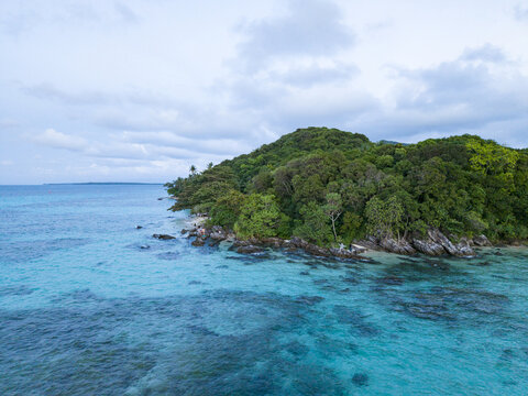 Aerial view of the lush, verdant Tanjung Gelam Beach contrasting with the turquoise waters, a tropical paradise captured from above, Karimunjawa, Central Java, Indonesia.
