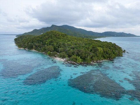 Aerial view of a lush tropical island fringed by turquoise waters and coral reefs, Tanjung Gelam Beach, Karimunjawa, Central Java, Indonesia.