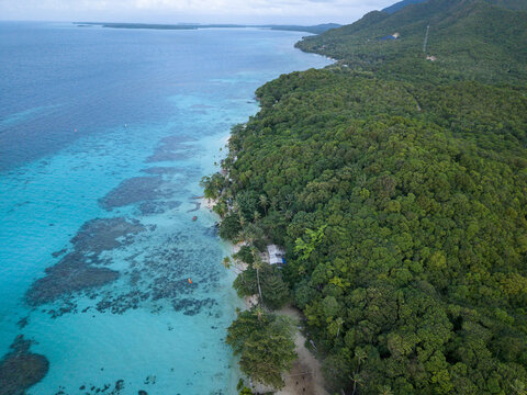 Aerial view of the coast where the turquoise sea meets the lush green forest, Tanjung Gelam Beach, Karimunjawa, Central Java, Indonesia.