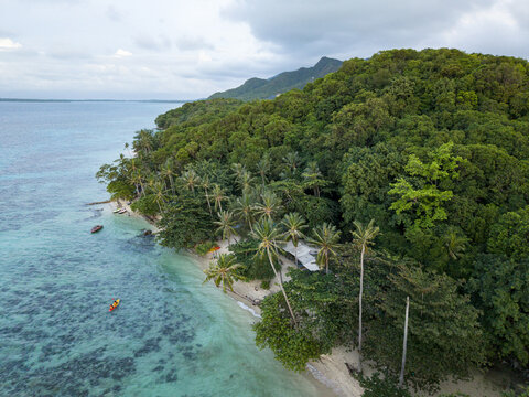 Aerial view of the beach with turquoise waters meeting the lush green forest, Tanjung Gelam Beach, Karimunjawa, Central Java, Indonesia.