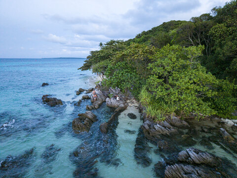 Aerial view of turquoise waters meet rocky shores, fringed by lush greenery, creating a stunning coastal contrast, Karimunjawa, Central Java, Indonesia.