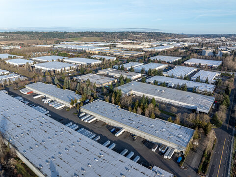 Aerial view of sprawling warehouses casting long shadows under the clear sky, a tableau of industrial might, Kent, Washington, United States.