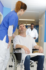 Obraz premium friendly nurse supporting smiling paralyzed man in a wheelchair