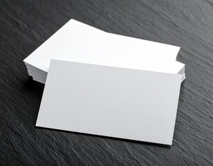 Stack of white business cards on a dark wooden surface viewed from above