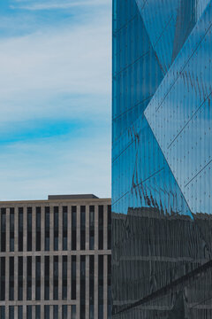 Angular blue glass skyscraper architecture facade rising into urban sky with modern geometry creating clean background texture for corporate design use