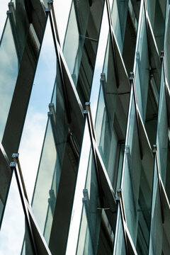 Abstract modern glass facade architecture with diagonal windows and steel reflection forming clean geometry for corporate background and design layouts