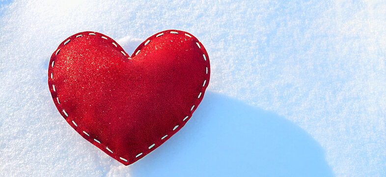 a banner of a stitched, red, sparkling heart on the snow on a frosty, sunny, winter day