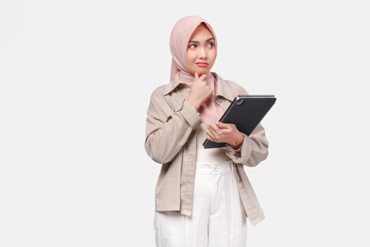 Confused young Asian woman wearing hijab is thinking hard while holding tab document.