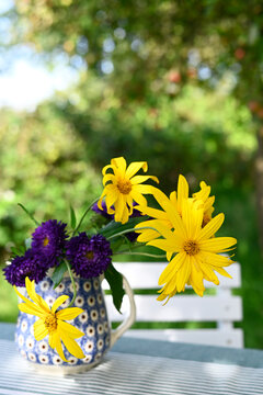 Yellow Jerusalem artichoke and purple aster in ceramic vase outdoors in autumn