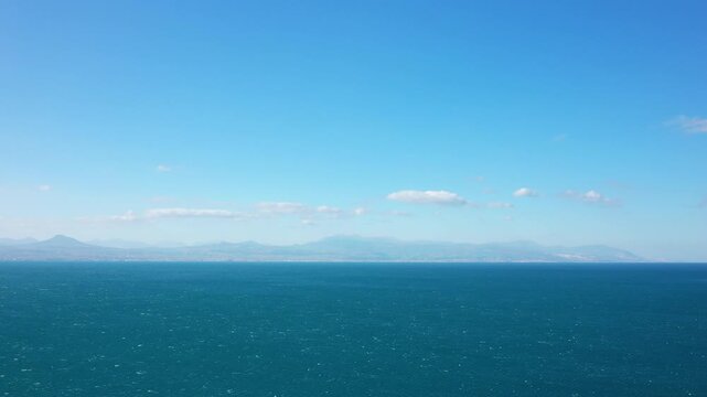 Wide view of the blue sea with distant mountains under a clear sky near Corinth, Greece. Calm and serene seascape perfect for travel and nature themes.