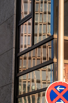 Urban parking sign with prohibition symbol on modern building facade windows in daylight showing city regulation detail with clean graphic design and contemporary street architecture