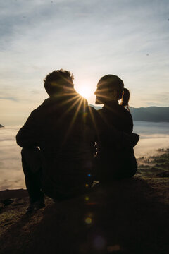 Couple sitting together at sunrise overlooking Mount Bromo volcano
