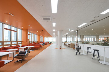Modern library or study area with orange accent wall and seating. © Namsun