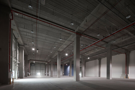 Empty industrial warehouse interior with concrete columns and high ceiling.