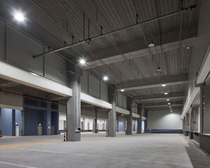 Empty warehouse interior with columns and daylight, industrial architecture.