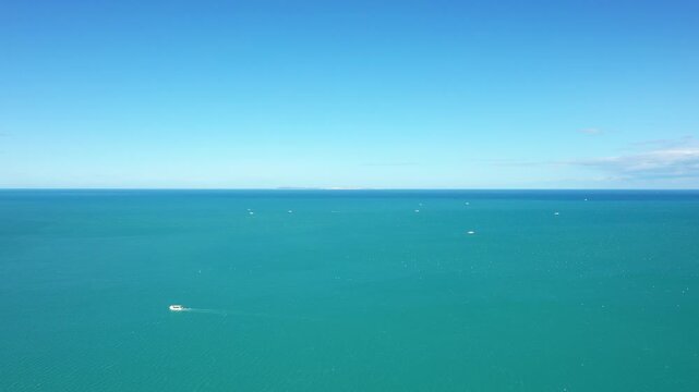 Wide aerial shot of the turquoise sea near Isola Varano Nature Reserve with scattered boats under a clear blue sky. Tranquil seascape ideal for travel and nature concepts.