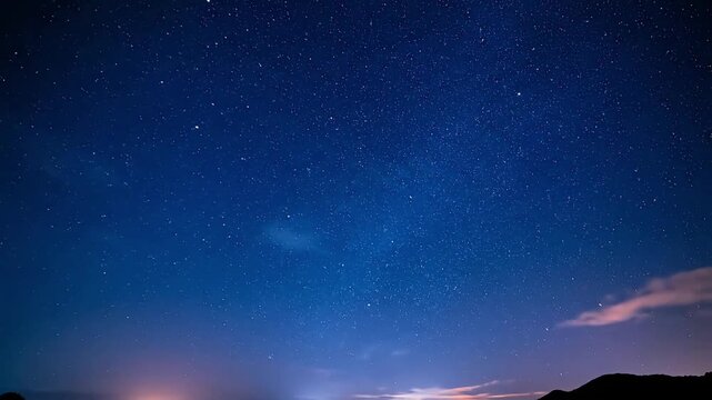 Countless brilliant stars slowly twinkle and majestically drift across a vast deep blue night sky, presenting an awe-inspiring celestial spectacle over distant illuminated horizons and subtle cloud fo