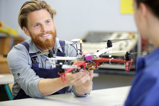portrait of young engineer fixing propeller of octocopter indoors