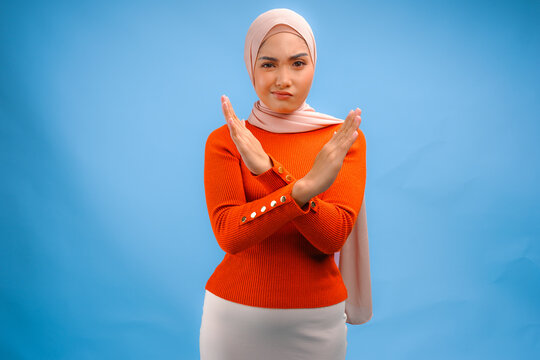 Pretty Asian Muslim woman wearing a hijab with hand gesture posing rejection or prohibition.
