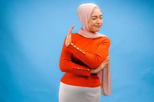 Cute Asian Muslim woman wearing a hijab with hand gesture posing rejection or stop.