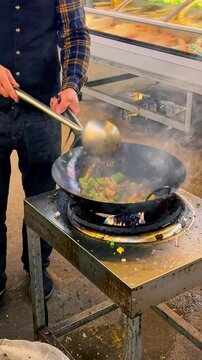 Chinese chef stir frying with fire in a wok pan