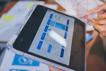 Close up ux developer and ui designer brainstorming about mobile app interface wireframe design on table with customer breif and color code at modern office.Creative digital development agency.