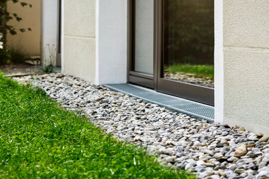 Drain Gravel Crushed Stone Drainage Along House Foundation Wall with Drainage Grate under Building Window.  