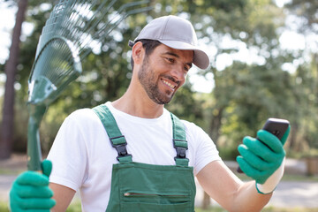professional sweeper using phone during the work in the garden