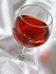 Naklejka premium Elegant glass of deep red wine resting gently on a soft white cloth, inviting a moment of indulgence Generative AI