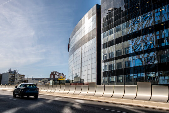 Glass facade architecture with curved roadway and car in La Defense Paris business district showing modern urban movement and design