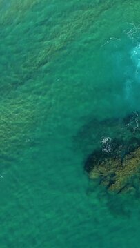 Drone shot of turquoise water and submerged rocks near the coast of Acciaroli, Italy. Sunlight highlights the clarity of the Mediterranean Sea.