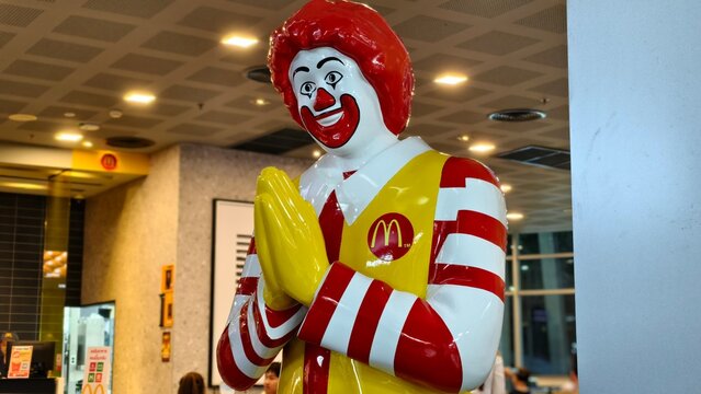 Ronald McDonald clown statue performing traditional Thai Wai greeting with red hair and yellow suit on November 21, 2025 at McDonald Union Mall Branch in Bangkok, Thailand.