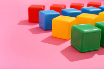 Obraz premium Colorful cubes on pink background, closeup