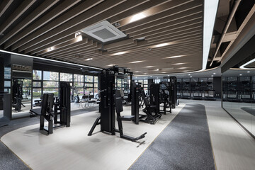 Empty modern fitness gym interior with cardio machines and strength training equipment.