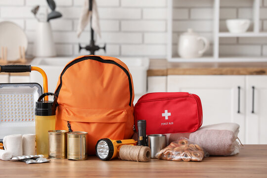 Orange emergency backpack with necessities on table in kitchen