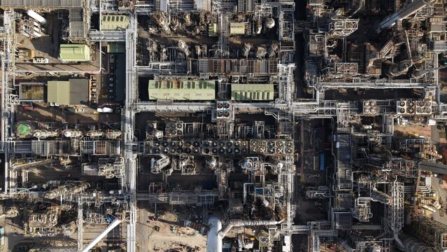 Aerial view of a sprawling industrial complex with a maze of pipes and structures casting long shadows in the afternoon sun, Immingham, United Kingdom.