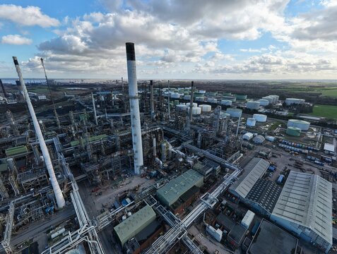Aerial view of the sprawling industrial complex of Humber Refinery, with its towering smokestacks piercing the sky against a backdrop of patterned clouds, Immingham, United Kingdom.