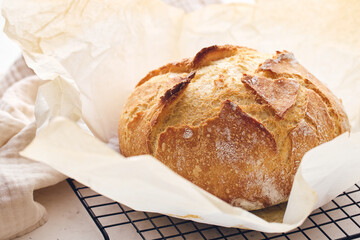 Round sourdough loaf resting on black wire cooling rack with beige linen towel. Perfect for baking, food blogs, and culinary projects