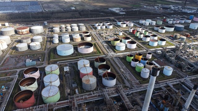 Aerial view of an industrial landscape, where metallic tanks and pipelines form a grid, contrasting with the earthy tones of the surrounding terrain, Immingham, United Kingdom.